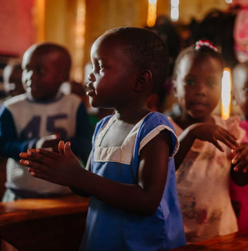 Small girl in Uganda clapping her hands in a classroom